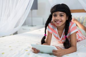 Smiling young girl playing games on tablet