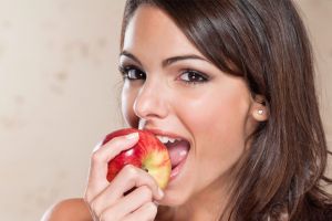 Smiling young woman eating apple | Orthodontic wellness